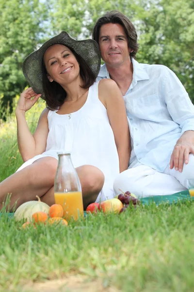 Paar sitzt auf dem Gras und isst Obst — Stockfoto