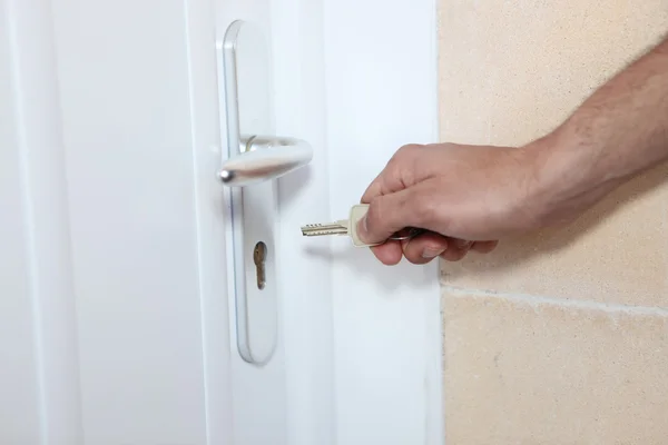 Человек кладет ключ в замок двери — стоковое фото