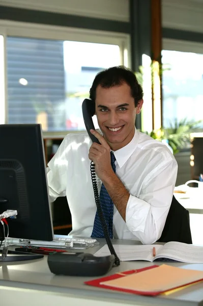 Affärsman vid sitt skrivbord som talar i telefon — Stockfoto