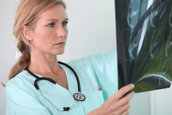 Verpleegster kijkt naar röntgenfoto — Stockfoto