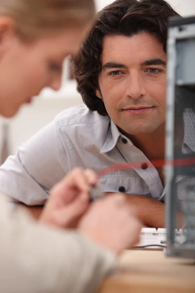 テレビを修理する女性を見ている男 — ストック写真