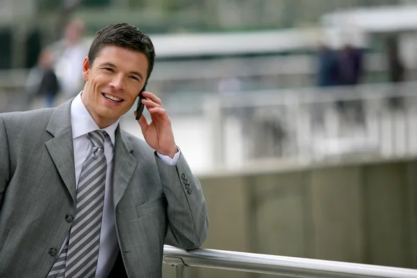 Businessman making phone call whilst leaning against railing — Stock Photo, Image