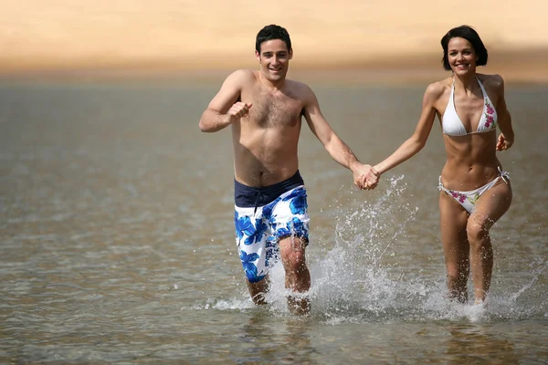 Joyeux couple courant à travers la mer — Photo