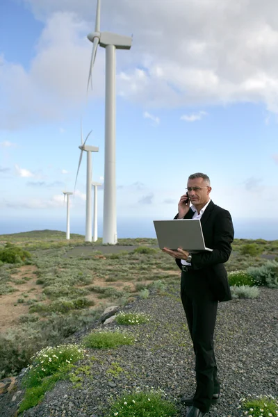Бизнесмен использует ноутбук на ветряной электростанции — стоковое фото
