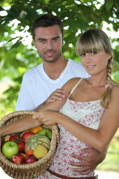 Jeune couple dans le parc avec panier de fruits — Photo