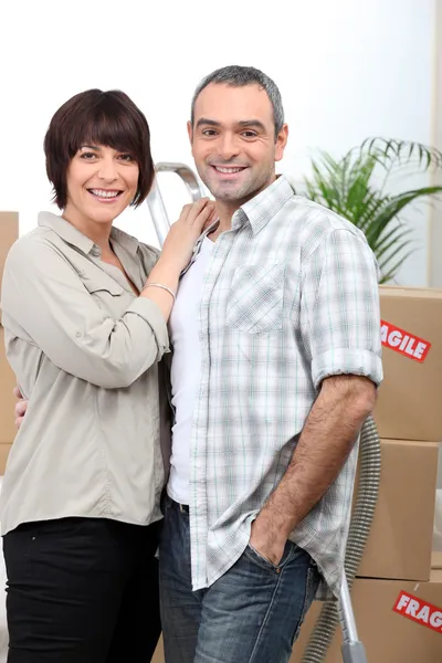 Um casal atrás de uma pilha de caixas dentro de uma casa — Fotografia de Stock