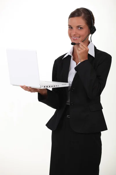 Žena drží notebook a nošení telefonu hlavové složení — Stock fotografie