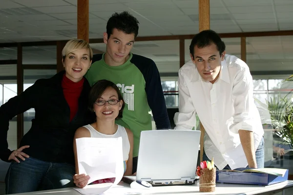 Молодая творческая команда, стоящая с ноутбуком — стоковое фото