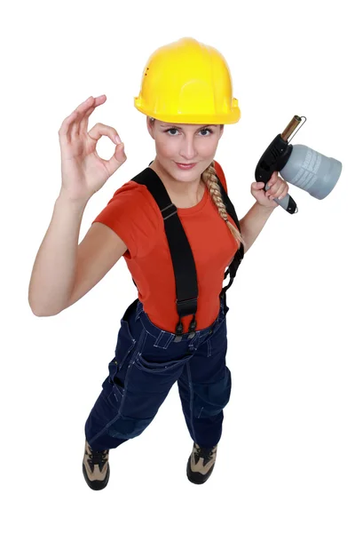 Tradeswoman håller en blåslampa och ge a-ok logga — Stockfoto