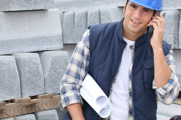 Bina planları ve cep telefonu ile inşaat işçisi — Stok fotoğraf