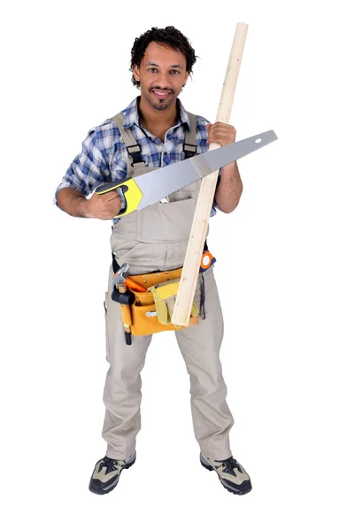Trabalhador segurando uma serra e um pedaço de madeira — Fotografia de Stock