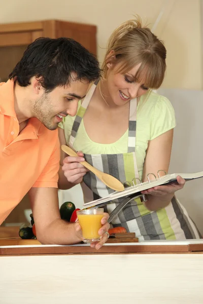 Couple with a recipe book in the kitchen — Stock Photo, Image