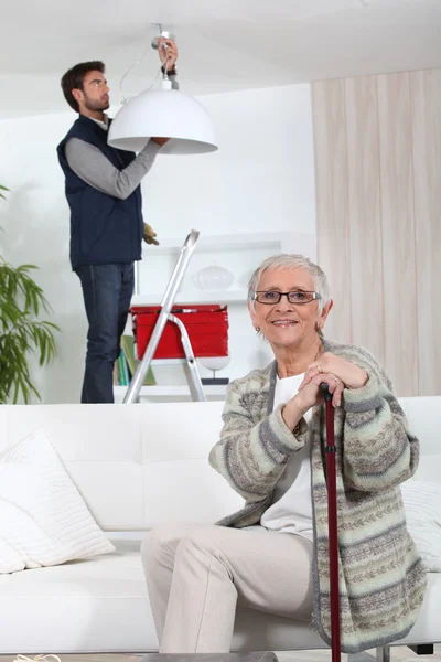 Junger Mann befestigt Lampe für ältere Frau — Stockfoto