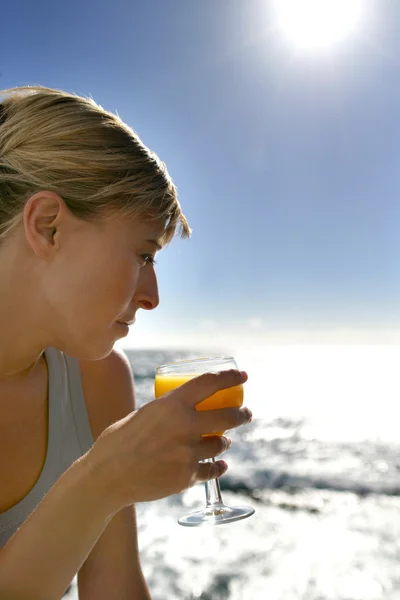Жінка має освіжаючий напій на пляжі — стокове фото