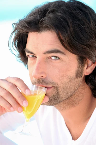 A man wearing a bathrobe and drinking orange juice — Stock Photo, Image