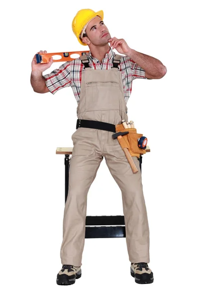 Carpenter holding a level and thinking — Stock Photo, Image