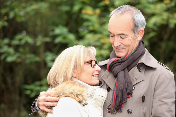 Vecchia coppia indossa vestiti caldi nella foresta ed esprime tenerezza — Foto Stock