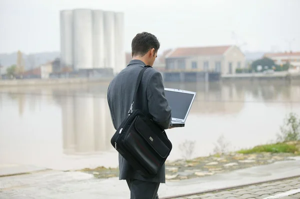 Бизнесмен ходит и работает над своим ноутбуком — стоковое фото