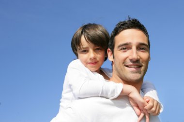 Little boy on his father's back clipart