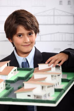 A little boy wearing suit and tie behind a district model clipart