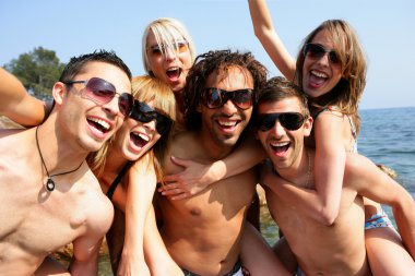 Group of young adults partying at the beach clipart