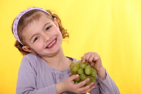 Little girl holding bunch of grapes — Stock Photo, Image