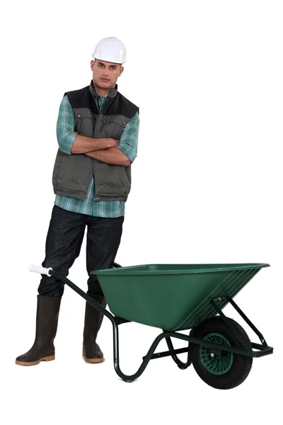 Un operaio in piedi accanto a una carriola . — Foto Stock