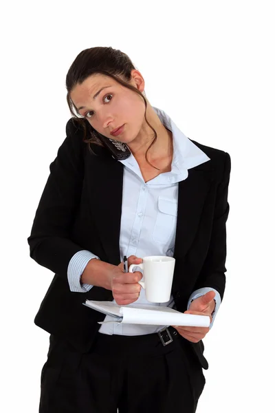 Vrouw aan de telefoon met notebook en koffie in de hand — Stockfoto