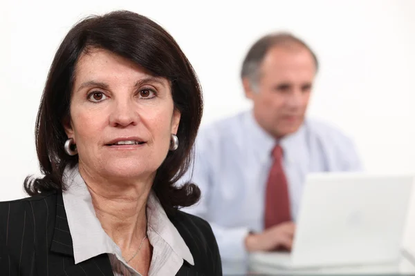 Mulher de negócios madura e homem usando um laptop — Fotografia de Stock