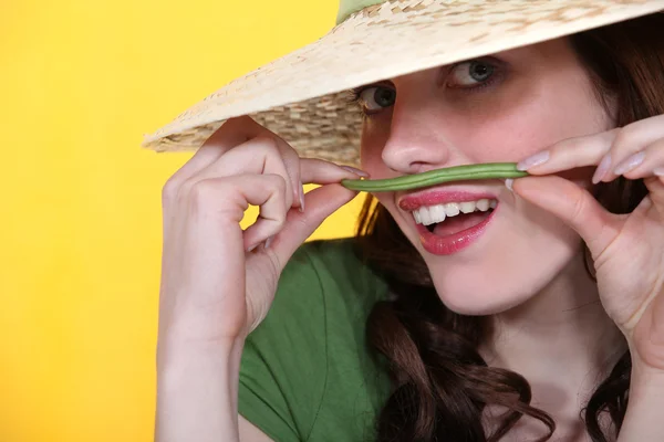 Mulher brincalhão segurando um feijão verde acima de seu lábio superior — Fotografia de Stock