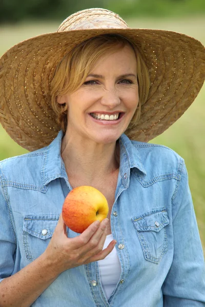 Frau lächelt mit einem Apfel — Stockfoto