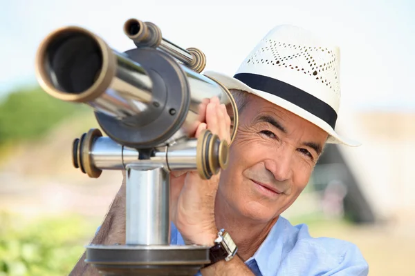 Senior assistindo através de um telescópio — Fotografia de Stock