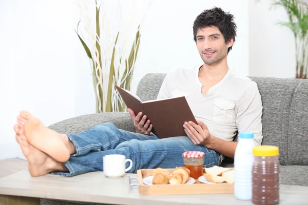 Mann liest beim Frühstück ein Buch — Stockfoto