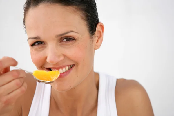 Kobieta jedzenie kromka Orange — Zdjęcie stockowe