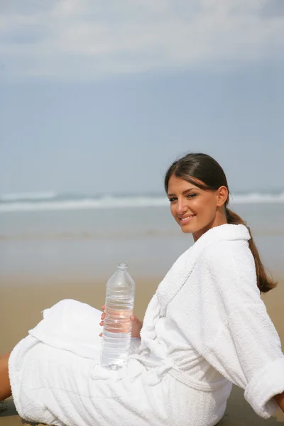 Mulher bebendo água na praia — Fotografia de Stock