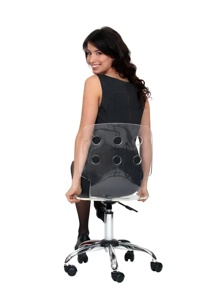 Mulher atraente sentada em uma cadeira giratória transparente — Fotografia de Stock