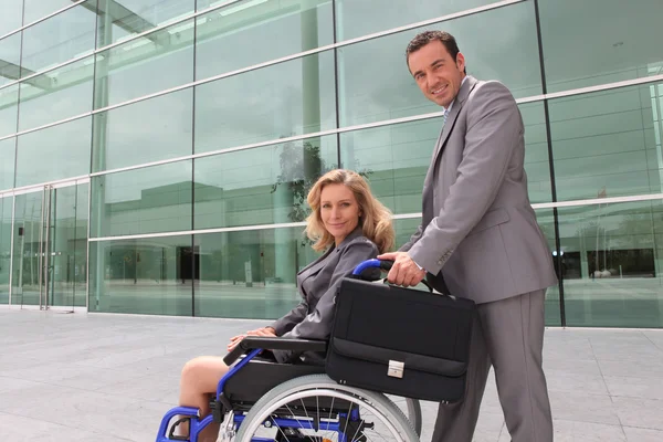 Жінка в інвалідному візку і чоловік допомагає — стокове фото