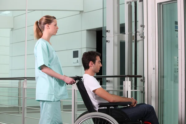 車椅子の看護師を助ける人 — ストック写真