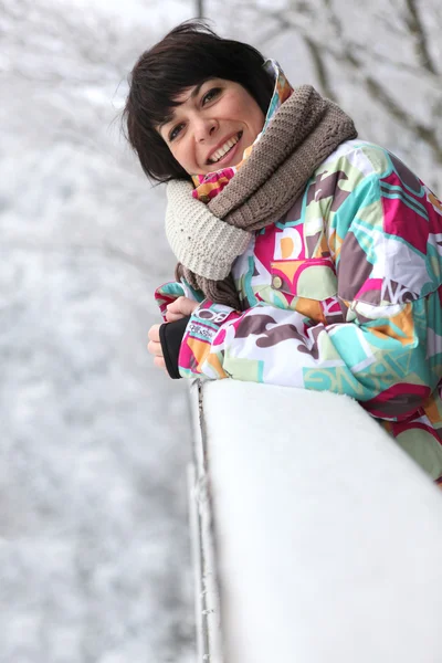 Woman leaning against a snow-covered ledge — Stock Photo, Image