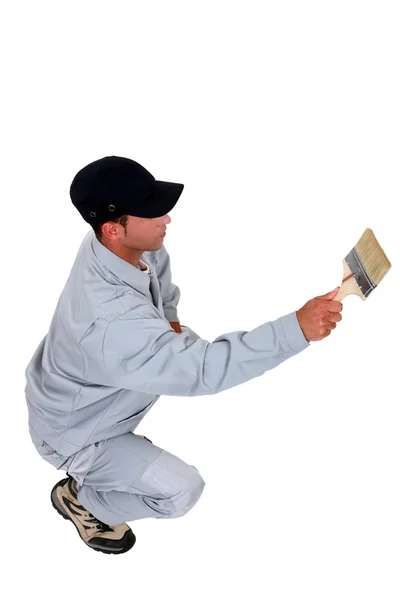 Agachamento comerciante pintando uma parede — Fotografia de Stock
