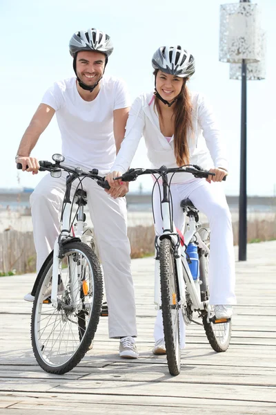 Couple riding bicycle wearing cycle helmet — Stock Photo, Image