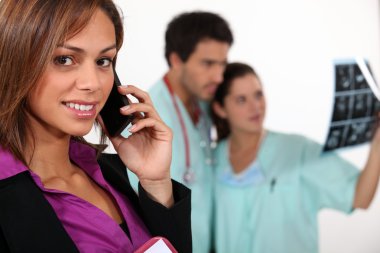 Businesswoman on phone and carers observing an x-ray clipart