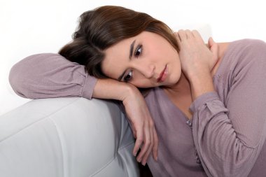 Sad woman sitting on a sofa clipart