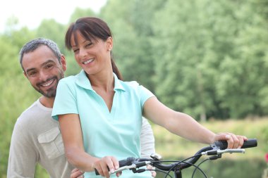 Couple riding bikes in countryside clipart