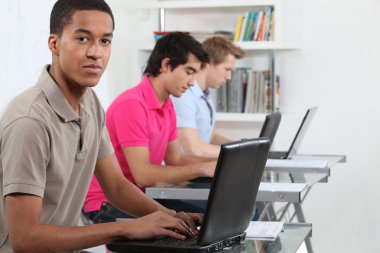 Young men working on their assignments in a computer lab clipart