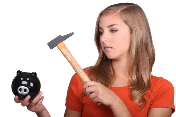 Blond tienermeisje smashing spaarvarken met de hamer — Stockfoto
