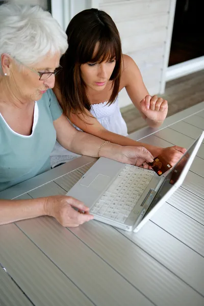 Mujer joven enseñando a su abuela habilidades informáticas — Foto de Stock