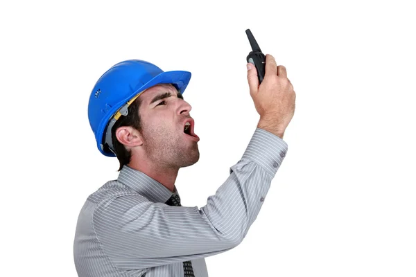 Homem de negócios irritado usando um capacete e gritando em seu walkie talkie — Fotografia de Stock