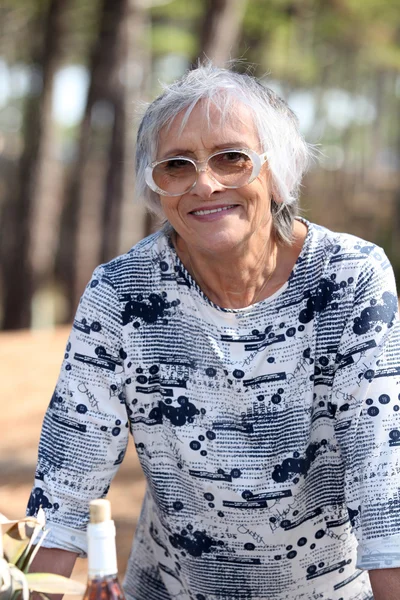 Older woman outdoors with a bottle of wine — Stock Photo, Image