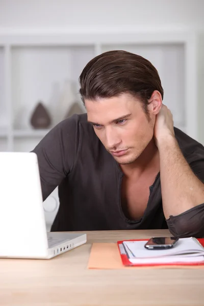 Młody przystojny mężczyzna pracuje na laptopie — Zdjęcie stockowe